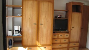 Ein Zimmer mit Holzausstattung, einem Fernseher und einer Kaffeemaschine.