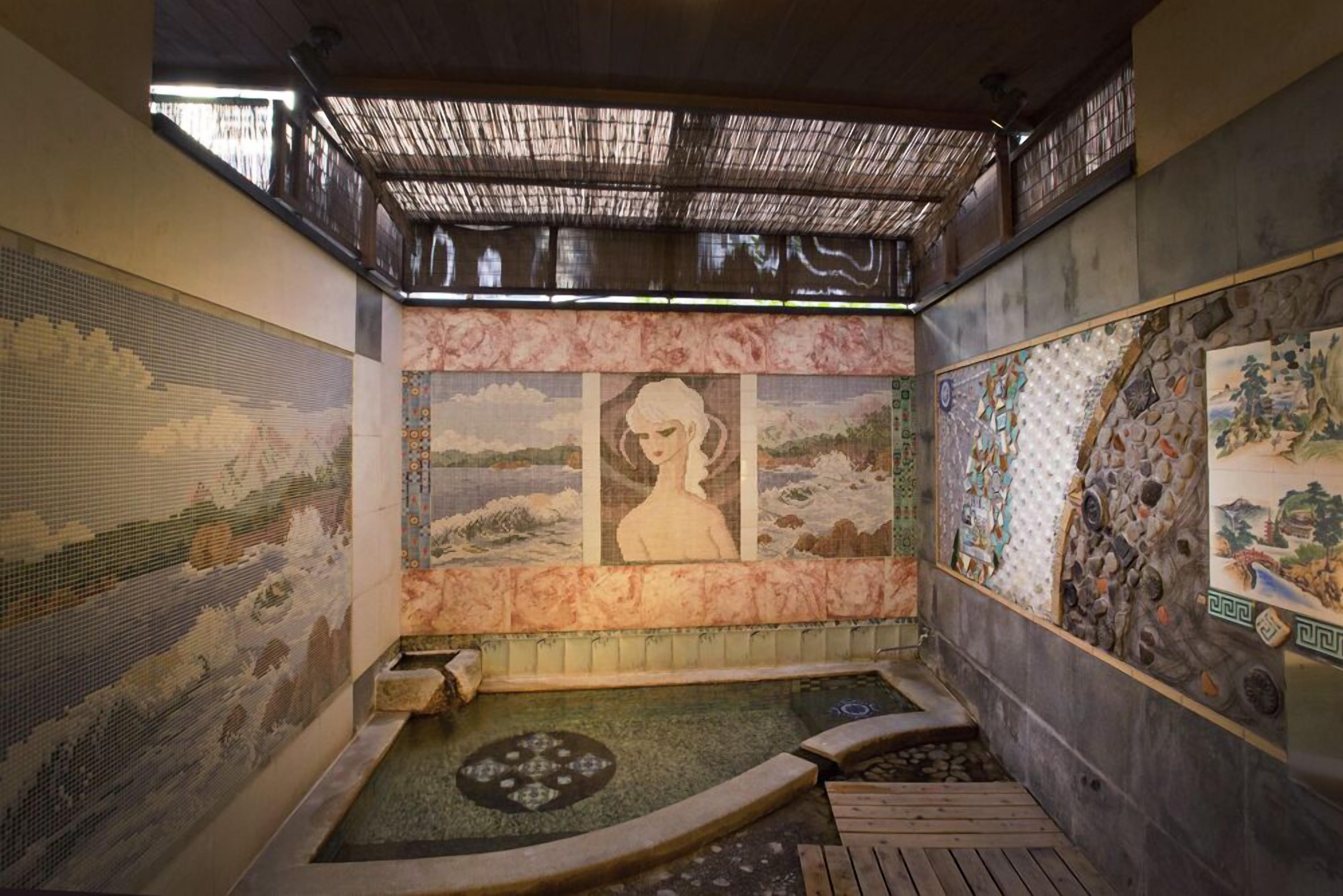 A traditional Japanese onsen with tatami flooring, a stone hot spring, and decorative murals.