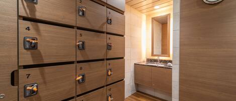 A row of wooden lockers numbered 1 to 12, a sink with a marble countertop, and a wall-mounted clock.