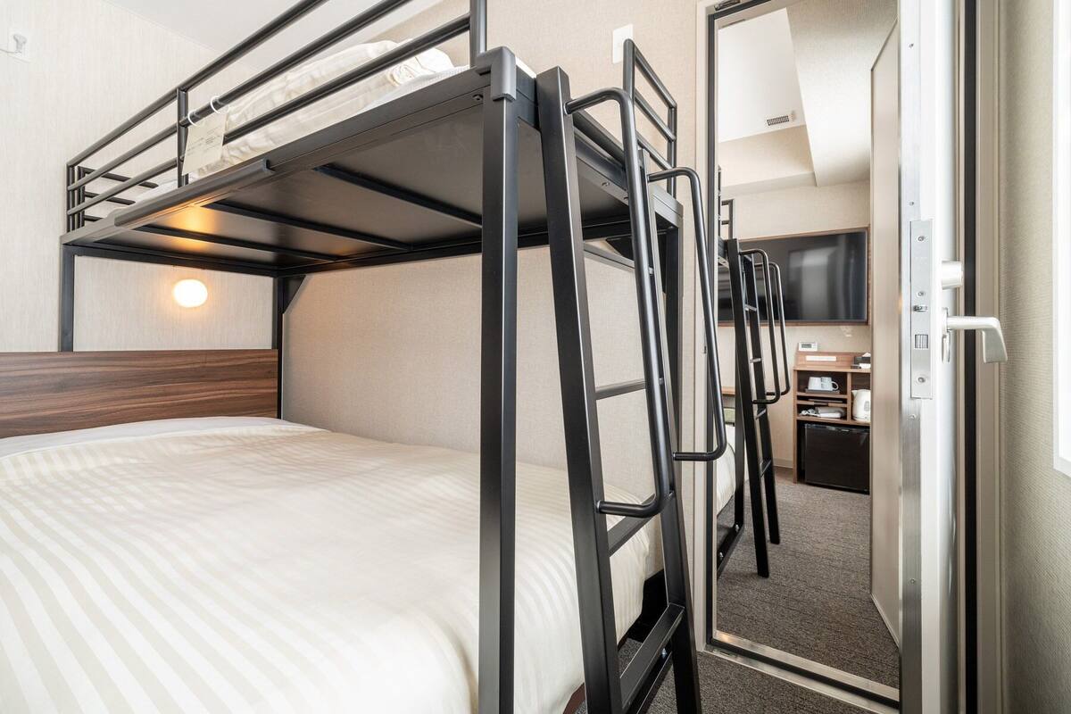 A bunk bed room with a desk and a television.