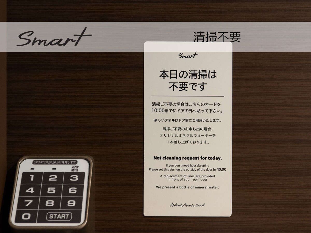 A hotel room with a 'Smart' sign, a not cleaning request sign, and a numeric keypad.