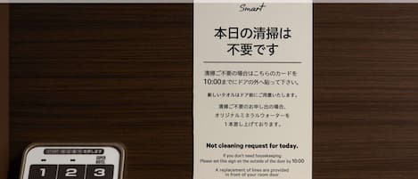 A hotel room with a 'Smart' sign, a not cleaning request sign, and a numeric keypad.