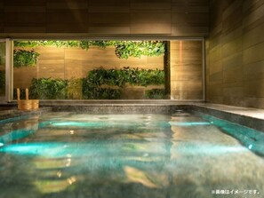 Un jacuzzi con pared de madera y follaje al fondo.
