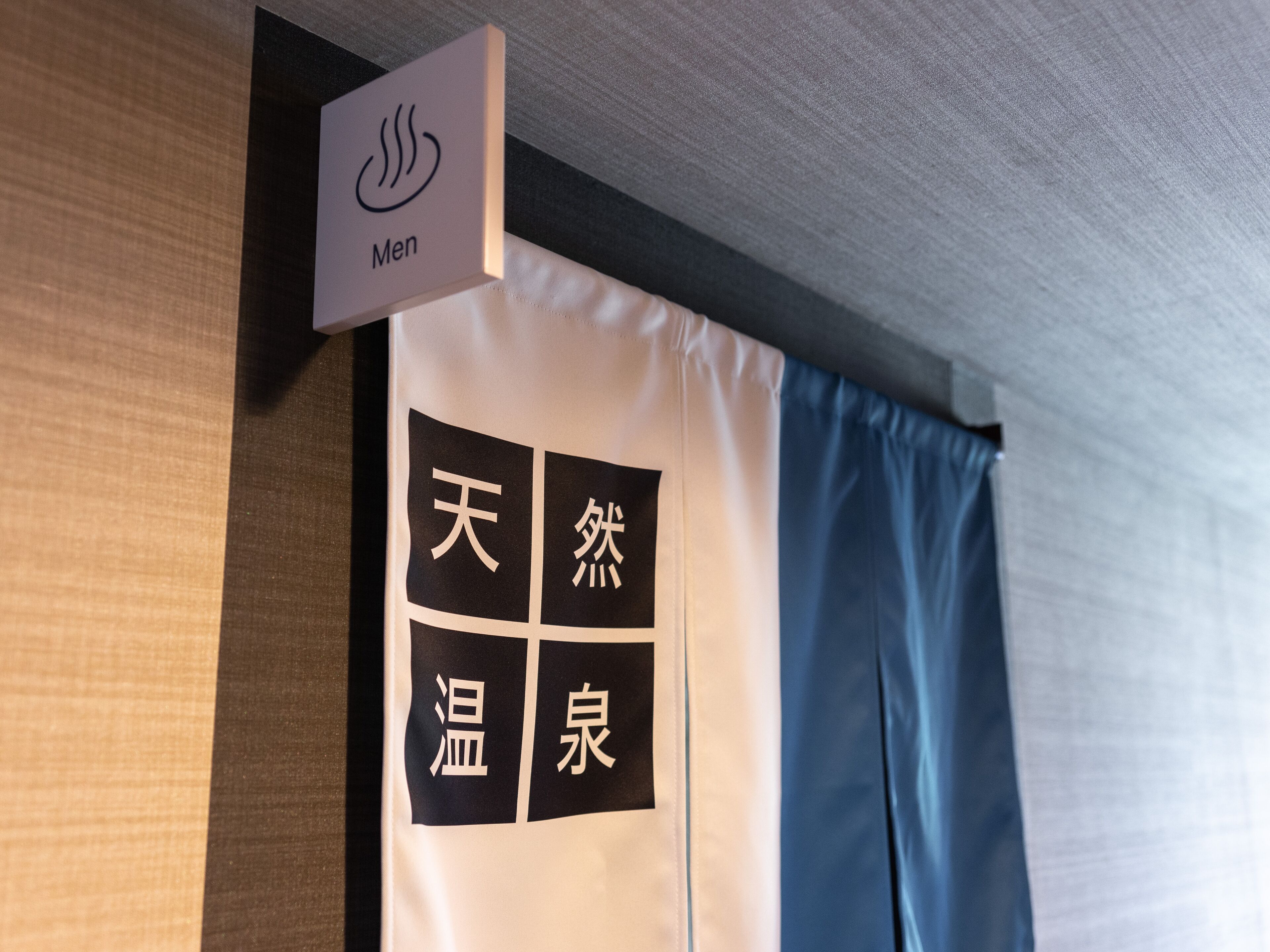 A sign indicating a men's restroom and a room with a curtain featuring Chinese characters.