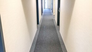 A long, narrow hallway with carpeted floors and beige walls. - Hotel Livemax Chiba Chuo Ekimae (Chiba)