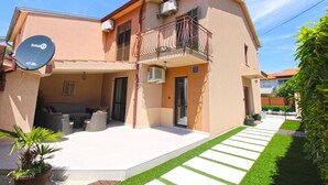 A two-story house with a balcony, satellite dish, and outdoor seating area.