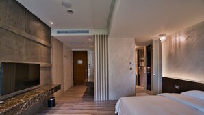 Una habitación de hotel moderna con una televisión de pantalla plana grande, una cama y suelo de madera.