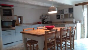 Una cocina con armarios de madera, una mesa de comedor y sillas. Hay un tazón rojo sobre la mesa.