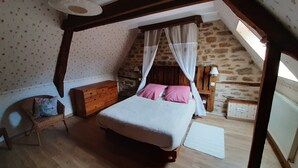 Un dormitorio abrigado en el ático, con cama, cómoda de madera y pared de piedra.