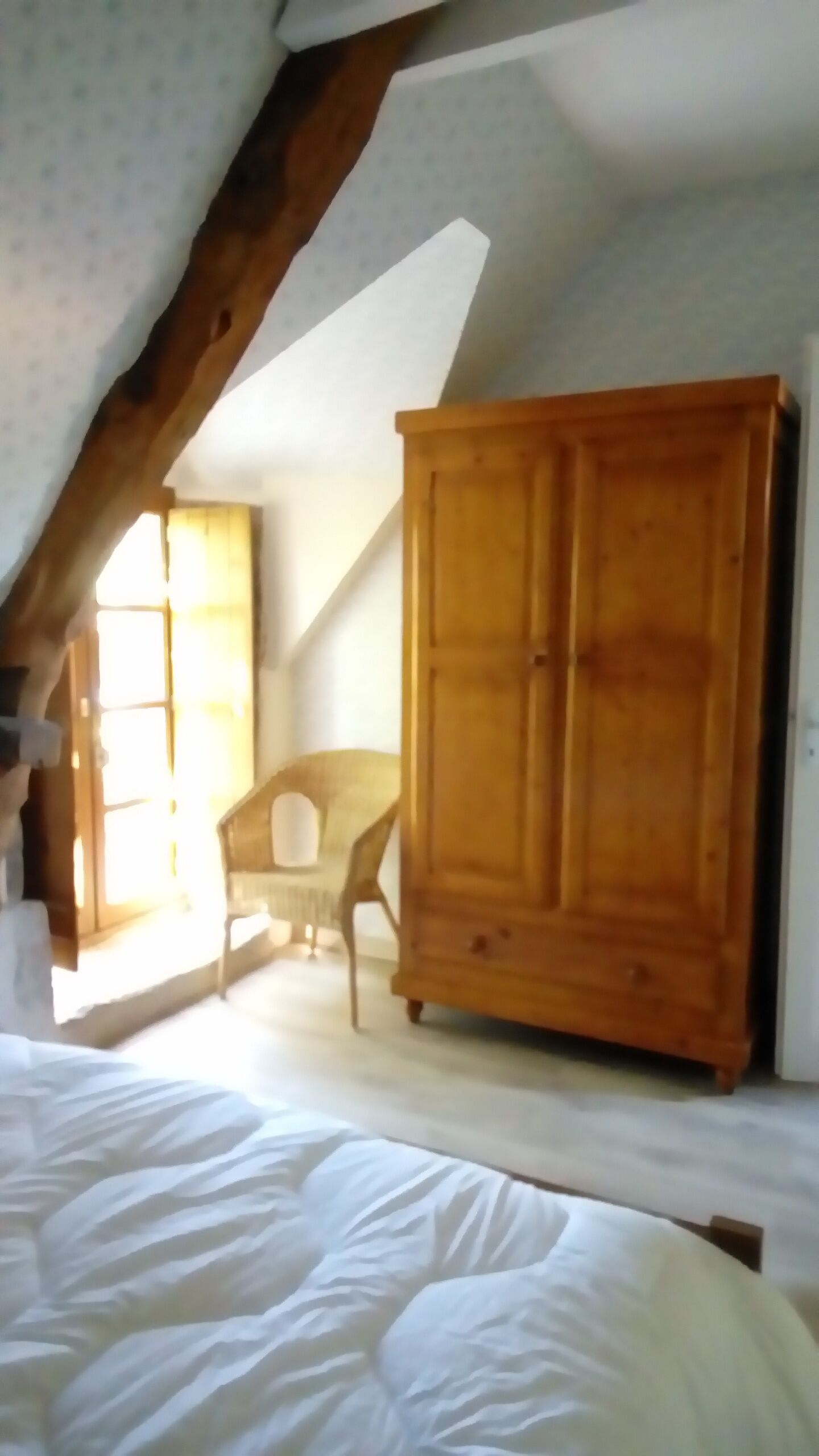 Una camera da letto con un letto grande, un'armadio in legno e una sedia.