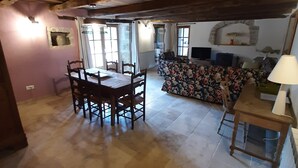 Un comedor rústico con una mesa y sillas de madera, un sofá floral y una chimenea de piedra.