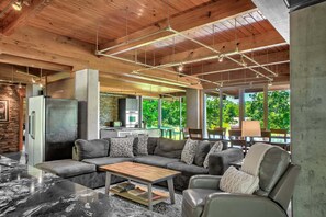 A modern living area with a sectional sofa, a wooden coffee table, and a large window offering a view of greenery.