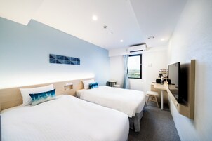 Una habitación de hotel con dos camas, un escritorio, un televisor y una ventana.