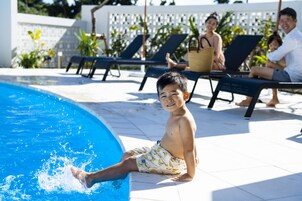 Una piscina al aire libre, sombrillas, sillones reclinables de piscina