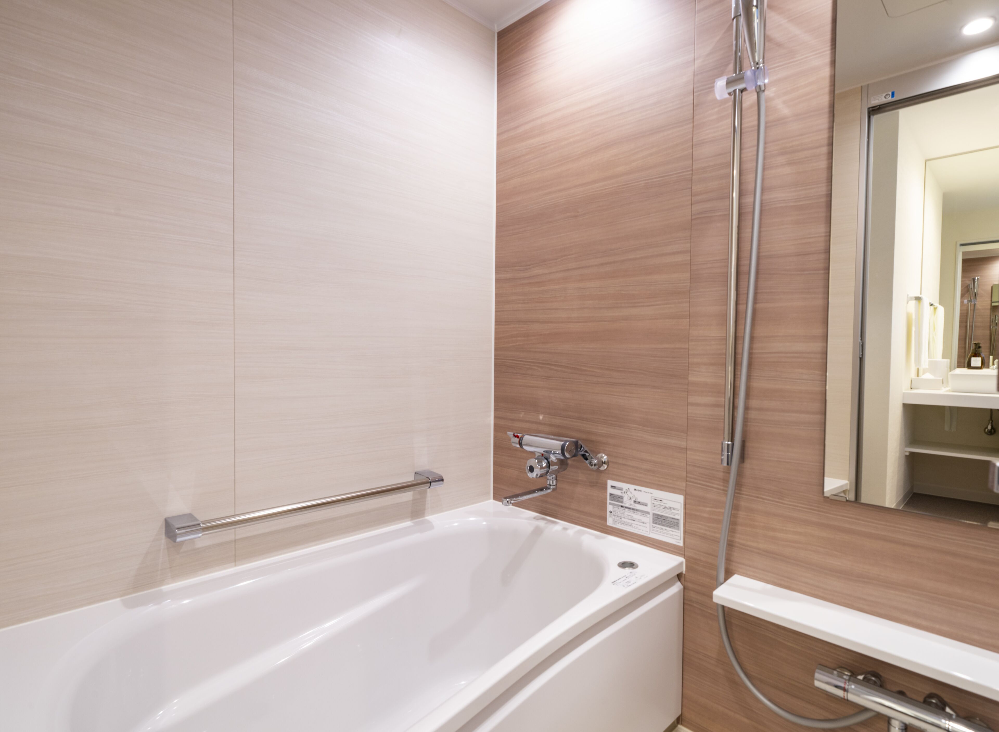 A modern bathroom with a white bathtub, a shower, and a vanity with a mirror.
