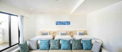 Una habitación de hotel con una cama grande, un sofá, una ventana con cortinas y una obra de arte azul en la pared.