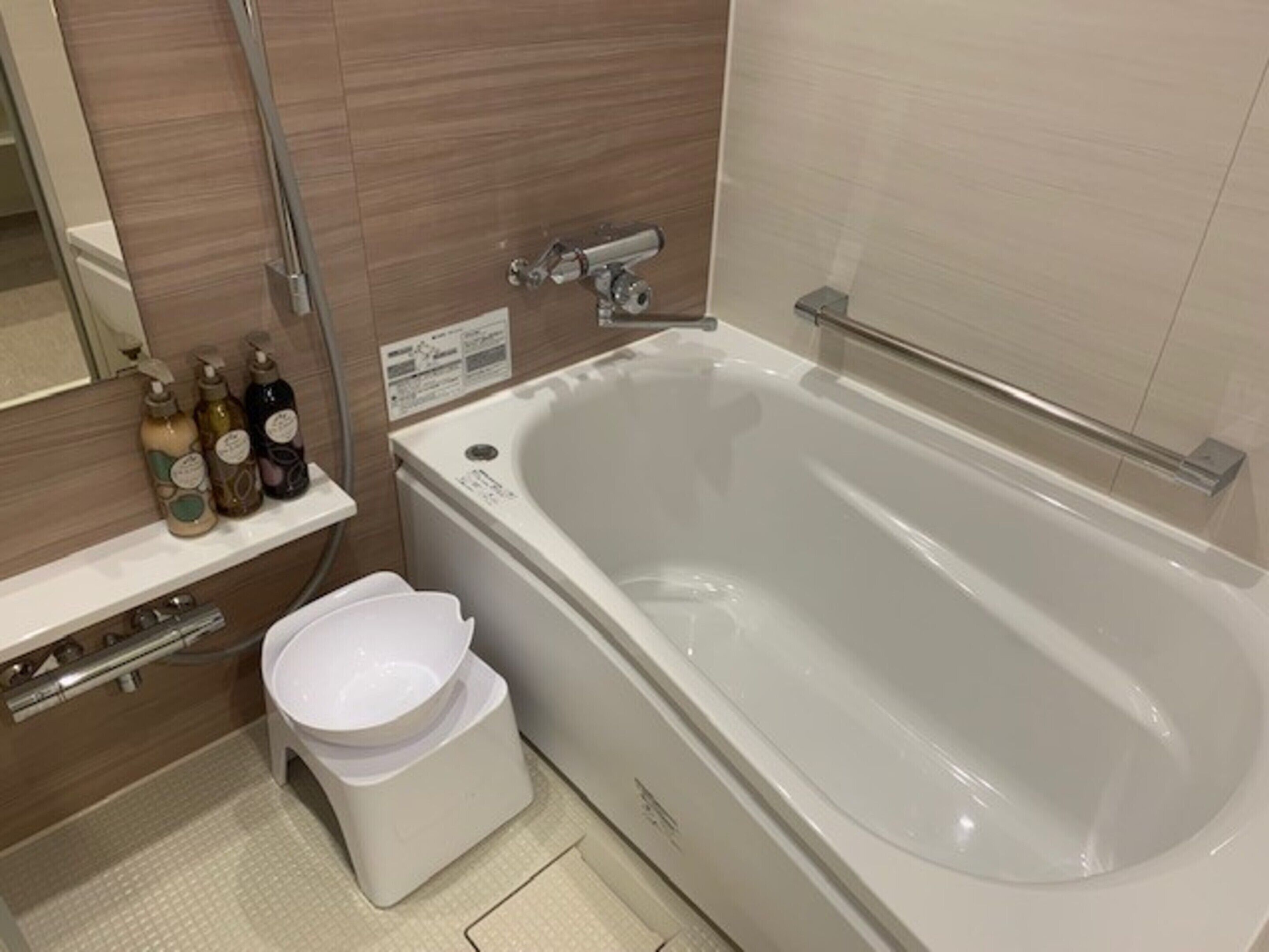 Un baño moderno con bañera, inodoro y un estante con artículos de aseo.