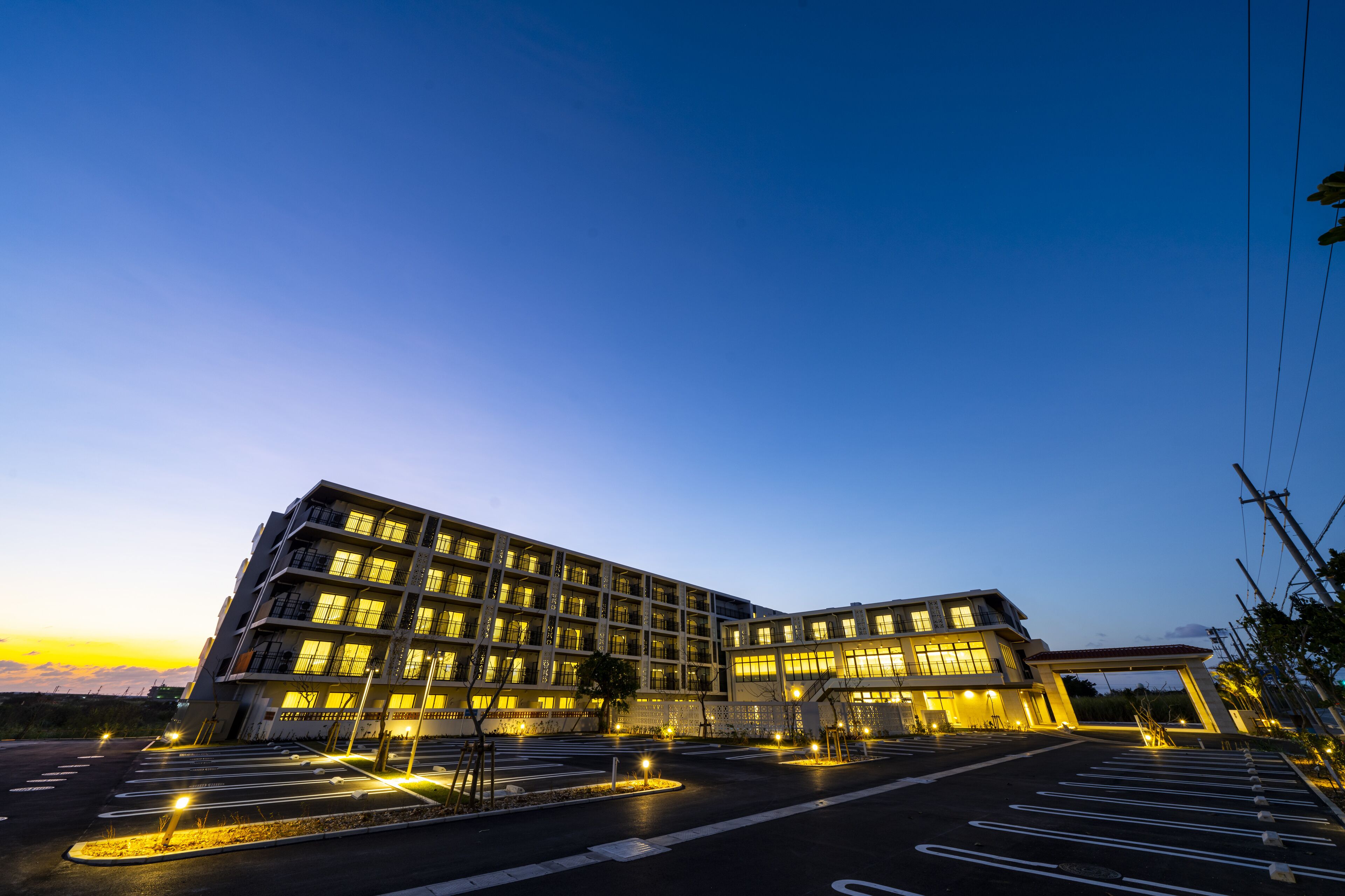 Een meerhoog hotel met een modern design, voorzien van een ruime parkeerplaats en een goed verlichte entree.