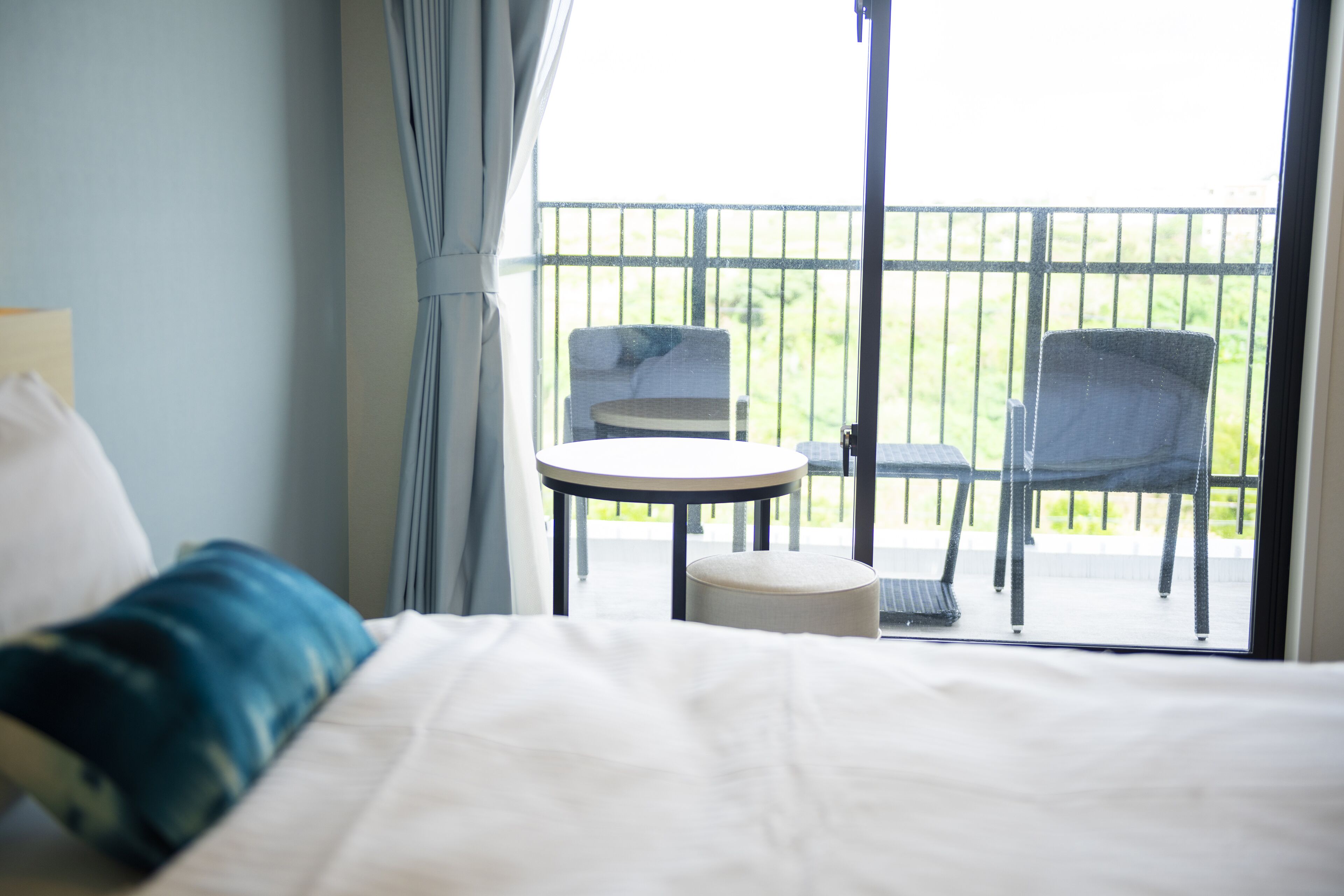 A hotel room with a bed, a round table, and two chairs on a balcony.