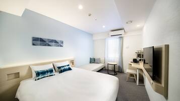 A hotel room with a large bed, a desk with a chair, a television, and an air conditioning unit.