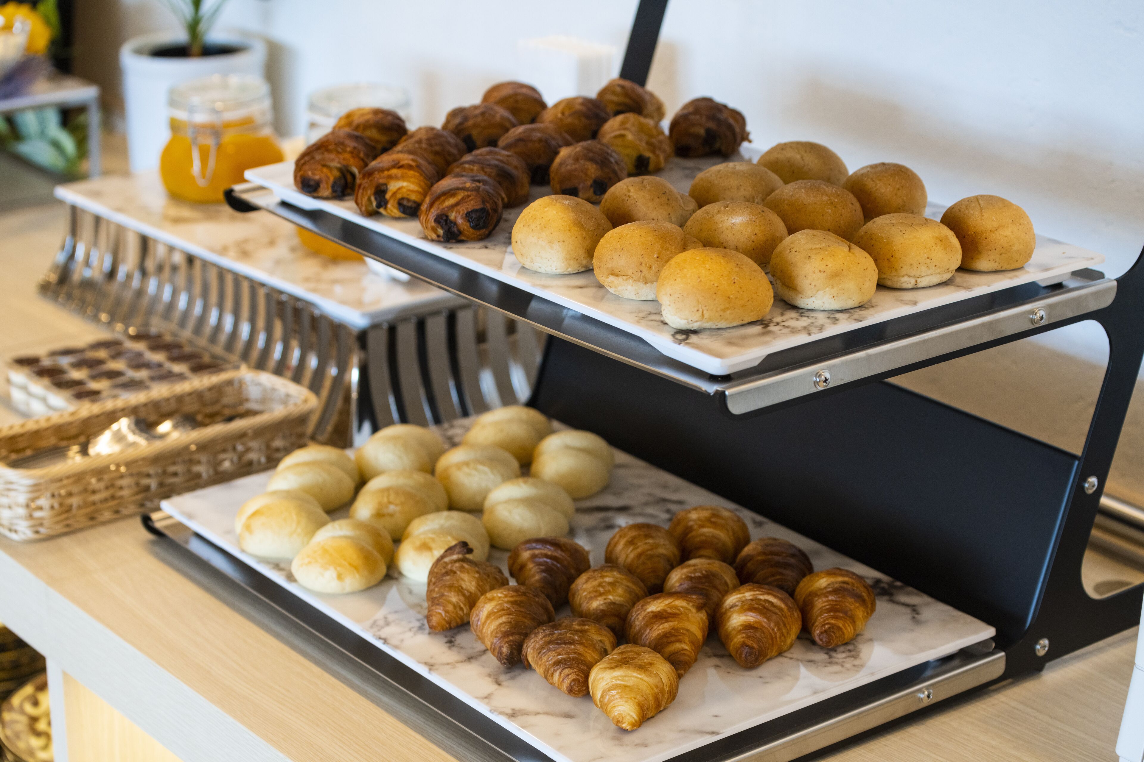 A buffet with various baked goods including croissants and rolls.