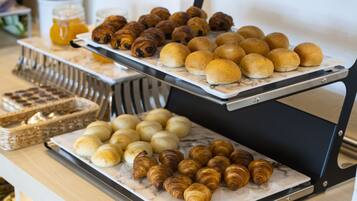 A buffet with various baked goods including croissants and rolls.