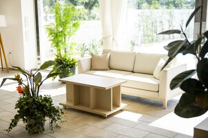 A modern living room with a beige sofa, a wooden coffee table, and potted plants.