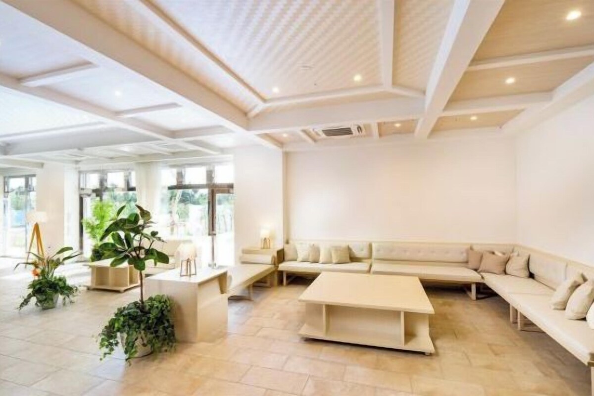 A spacious living area with a large sectional sofa, a coffee table, and potted plants.