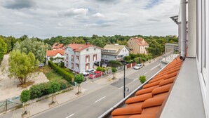 A residential street with houses, a clear sky, and a view of the road from a window with orange blinds. - Apartamenty Nadmorskie Sun & Snow (Sopot)