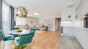A modern living room with a round marble table, teal chairs, and a grey sofa. - Apartamenty Nadmorskie Sun & Snow (Sopot)