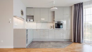 A modern kitchen with grey cabinets, a built-in oven, and a coffee machine. - Apartamenty Nadmorskie Sun & Snow (Sopot)