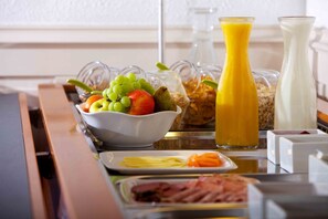 Un bufé de desayuno con frutas, jugos y diversas opciones para el desayuno.