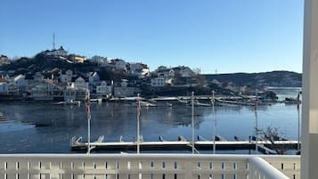 Varanda com vista para um porto, barcos e edifícios do outro lado da água.