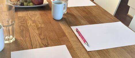A wooden conference table with water bottles, a plate of fruit, and a pink pen on a white paper.