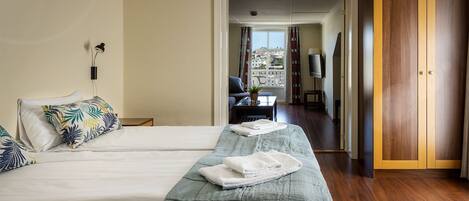 A hotel room with a large bed, a desk, a chair, and a view of the city through the window.