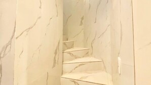 A marble staircase with a modern design, leading to a bright area with a light fixture. - Reimi Mondo (Tokyo)
