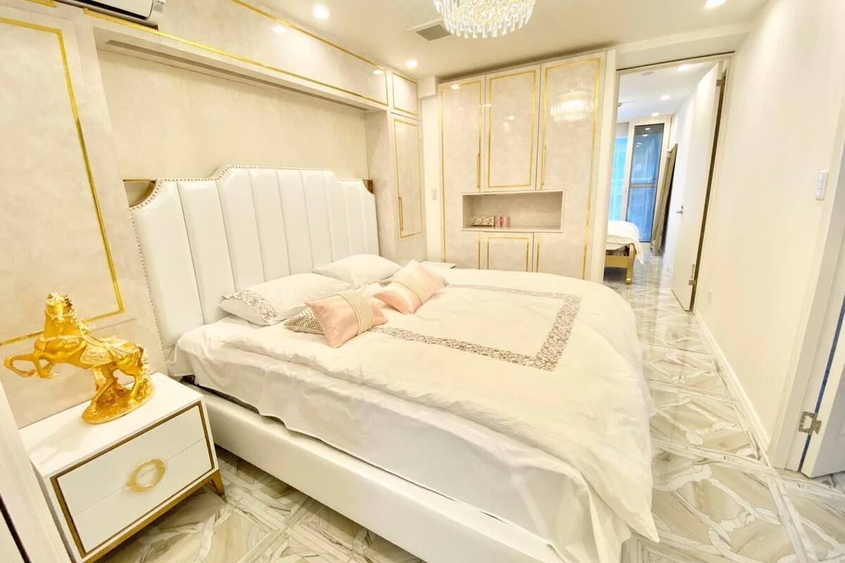 A luxurious bedroom with a large bed, a nightstand, a decorative horse statue, and a chandelier.
