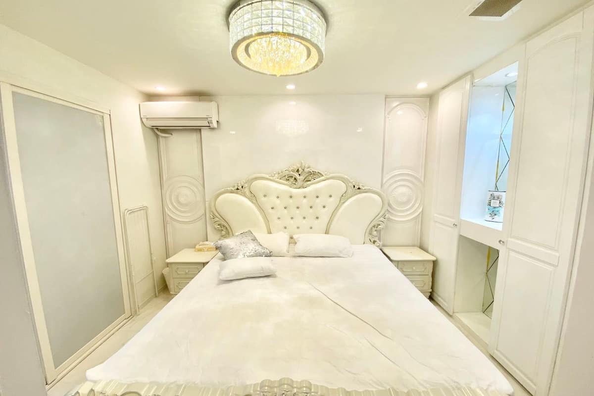 A bedroom with a large bed, ornate headboard, and a chandelier.