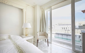 A hotel room with a large bed, a chair, a nightstand with a lamp, and a view of the city through large windows. - Reimi Mondo (Tokyo)
