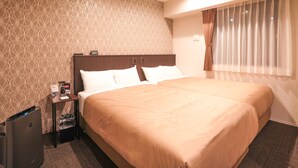 Habitación de hotel con una cama grande, una mesita de noche, un escritorio y una ventana con cortinas.