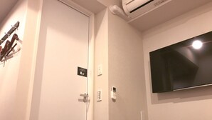 Habitación de hotel con cama, televisión montada en la pared, una puerta y aire acondicionado instalado en la pared.