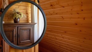 Puinen seinä, jossa on pyöreä peili, joka heijastaa kaappia ja maljakkoa, jossa on kukkia.