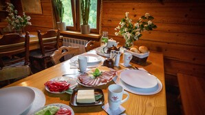Puinen ruokapöytä, jonka päällä on lautasia, aterimia ja erilaisia ruoka-aineita.