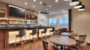 A modern kitchen with a bar area, wooden flooring, and a large window providing natural light.