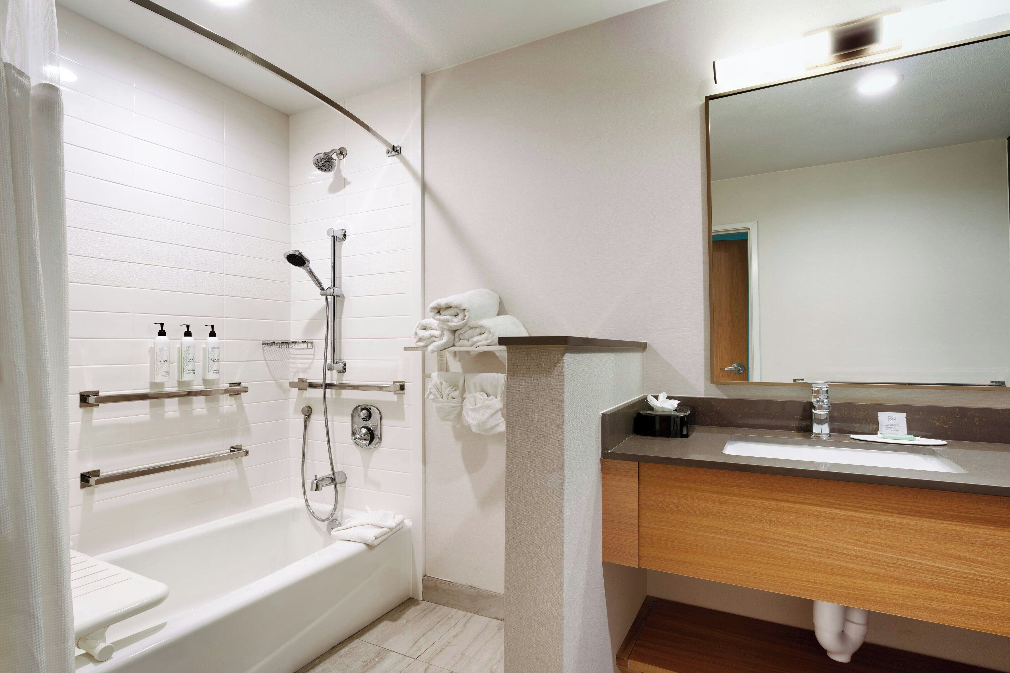 A modern bathroom with a bathtub, shower, and vanity with a mirror.