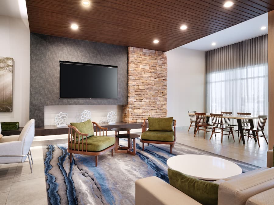 Ein moderner Lounge-Bereich mit Flachbildfernseher, Wandverkleidung aus Stein und bequemen Sitzmöglichkeiten.