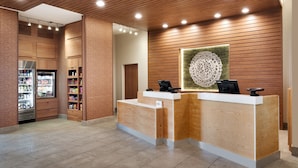 A reception area with wooden paneling, a reception desk, a refrigerator stocked with beverages, and a decorative wall piece.