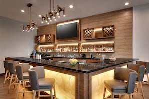 A modern bar area with a large island, bar stools, and a flat-screen TV mounted on the wall. - Fairfield by Marriott Inn & Suites Houston League City (League City)