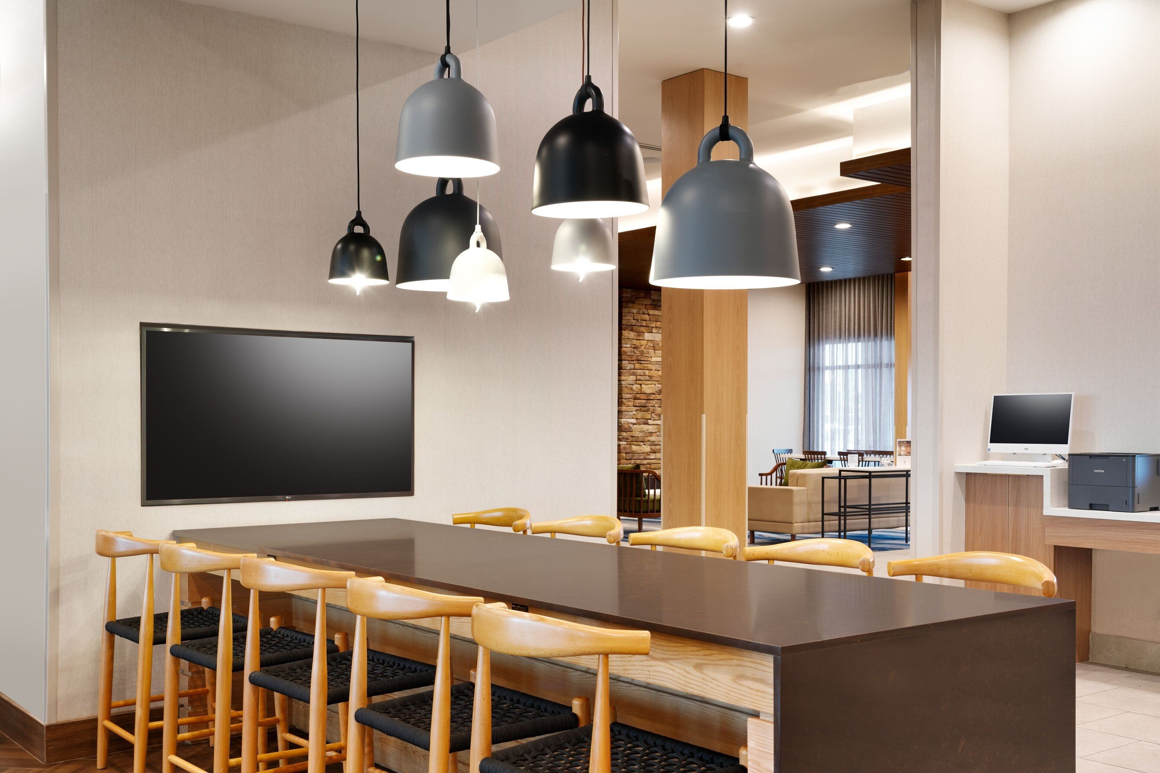 A modern conference room with a long table, multiple chairs, and pendant lighting.