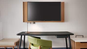 A modern office space with a large blackboard, a desk, a green chair, and a small stool.